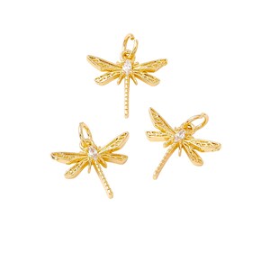 May include: Three gold dragonfly charms with clear crystal accents. Each charm has intricate details and a loop for attaching to jewelry.