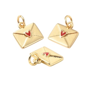 May include: Three gold-colored envelope charms with a red heart detail. The charms are in a three-dimensional design, with a loop at the top for attaching to a necklace or bracelet. The background is white.