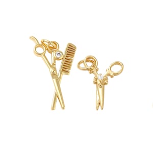 May include: Gold-colored charm pendants featuring miniature barber tools. One pendant shows crossed scissors and a comb, while the other displays a pair of scissors. Both charms have a small, clear gem. The pendants are designed for jewelry making.