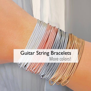 May include: A stack of silver, rose gold, and gold guitar string bracelets. Guitar String Bracelets. More colors!