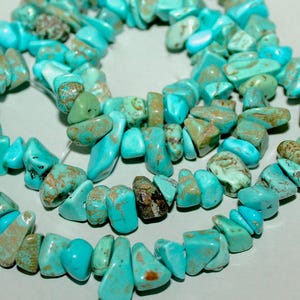May include: Strands of turquoise gemstone beads. The beads are a vibrant turquoise color with brown and green inclusions. The irregular, chip-like shapes are strung together, creating a natural and earthy aesthetic. Ideal for jewelry making.