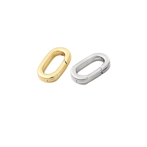 May include: Two oval-shaped clasps, one gold-toned and one silver-toned, are displayed against a white background. The clasps are open, showcasing their functionality. These jewelry findings are ideal for necklaces and bracelets.