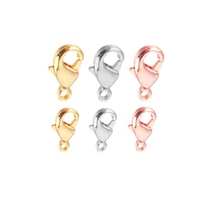 May include: Six metal lobster claw clasps in gold, silver, and rose gold. These clasps are used for jewelry making and are shown against a white background. The clasps are in a variety of finishes.