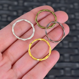 May include: Four metal jump rings in different finishes: silver, gold, bronze, and copper. The rings have a textured, hammered finish and are all the same size.