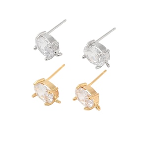 May include: A set of four earrings featuring oval-shaped clear cubic zirconia stones. Two earrings are silver-toned and two are gold-toned.