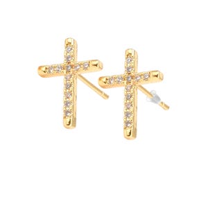 May include: A pair of gold cross earrings with clear cubic zirconia stones.