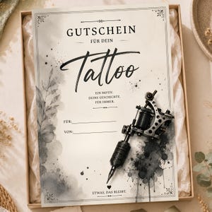Könnte beinhalten: Ein rechteckiger Gutschein mit cremefarbenem Hintergrund, schwarzer Schrift und grauen Aquarell-Blattillustrationen. Der Text lautet GUTSCHEIN FÜR DEIN Tattoo, EIN MOTIV. DEINE GESCHICHTE. FÜR IMMER. FÜR:, VON: und ETWAS, DAS BLEIBT. Eine schwarze Tätowiermaschine liegt darauf.