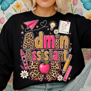 Könnte beinhalten: Ein schwarzes Sweatshirt mit dem Text Admin Assistant in goldenem Leopardenmuster und Pink. Das Design enthält ein rosa Papierflugzeug, eine Glühbirne, einen Notizblock mit Text, einen rosa Buntstift, einen gelben Bleistift, ein rosa Lineal und eine Schleife.
