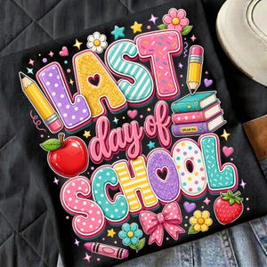 May include: Black t-shirt with a colorful graphic that says "LAST day of SCHOOL." The design includes a red apple, pencils, books, flowers, and a bow. The letters are decorated with patterns and glitter.
