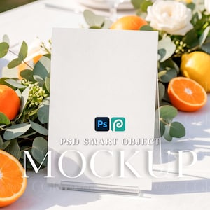 Puede incluir: Un soporte vertical rectangular para carteles hecho de acrílico transparente, con el texto PSD SMART OBJECT MOCKUP y dos pequeños iconos cuadrados en azul y turquesa. El cartel se muestra sobre una superficie blanca rodeado de naranjas y rosas.