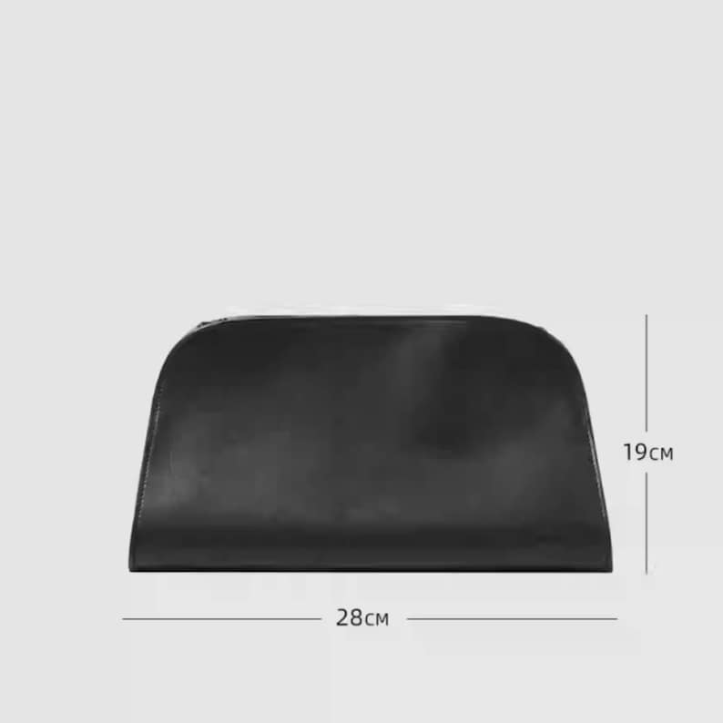 May include: A black clutch purse with a curved top and a zipper closure. The purse is 11 inches wide and 7.5 inches tall. The bag is made of a smooth, solid material and is set against a light gray background.