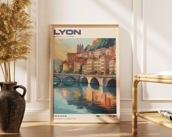 May include: A vertical travel poster print featuring a stylized illustration of Lyon, France, with a stone bridge over a river, historic buildings, and a cathedral. The text LYON and FRANCE are printed in dark blue, with coordinates at the bottom.