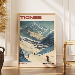 May include: A vertical wall art print featuring a stylised illustration of the Tignes mountain range in France. The poster displays snow-covered peaks, a small village, and skiers on a slope. The text TIGNES and FRANCE are printed in red.