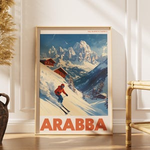 Könnte beinhalten: Ein vertikales Reiseplakat mit einem Skifahrer in roter Jacke, der einen verschneiten Berghang in Arabba hinunterfährt. Die Illustration zeigt Holzhütten, schneebedeckte Gipfel und den fetten orangefarbenen Schriftzug ARABBA unten.