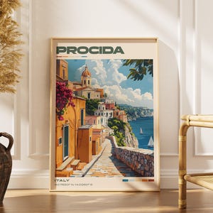 May include: A framed art print featuring a colorful illustration of Procida, Italy. The artwork depicts a coastal town with buildings, a church, and a road leading to the sea. The print includes the text "PROCIDA" and "ITALY" with coordinates.