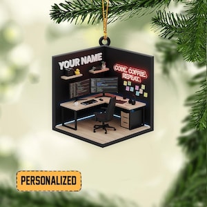 May include: A personalized Christmas ornament shaped like a miniature office. The ornament features a desk with dual monitors, a keyboard, and a black office chair. The text "YOUR NAME" and "CODE COFFEE REPEAT" are displayed. The word "PERSONALIZED" is also visible.
