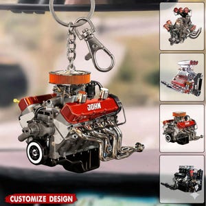 May include: A red and silver engine keychain with the name "JOHN" on the engine cover. The keychain has a silver chain and clasp. The words "CUSTOMIZE DESIGN" are at the bottom of the image. Additional engine images are in the background.