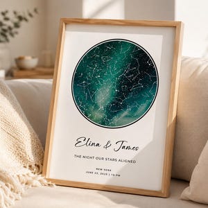 Könnte beinhalten: Ein gerahmter vertikaler Druck mit einer kreisförmigen Sternenkarte in Dunkelgrün und Schwarz. Unter dem Kreis steht der Text Elina & James, THE NIGHT OUR STARS ALIGNED, NEW YORK, JUNE 25, 2025 | 10:PM. Das Bild befindet sich in einem hellen Holzrahmen.