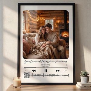 May include: A framed print with a photograph of a couple on a sofa, set in a warm, inviting room. The print has the text "Your Love sounds like my forever favorite song" and "Love Song" by Selena Gomez, with a music player design.