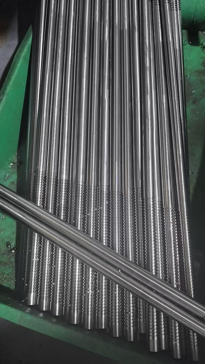 May include: A close-up shot of numerous, parallel, cylindrical metal rods. The rods are silver in color and have a textured pattern near the ends. The arrangement suggests a manufacturing or industrial setting. The rods are neatly aligned, creating a sense of order.