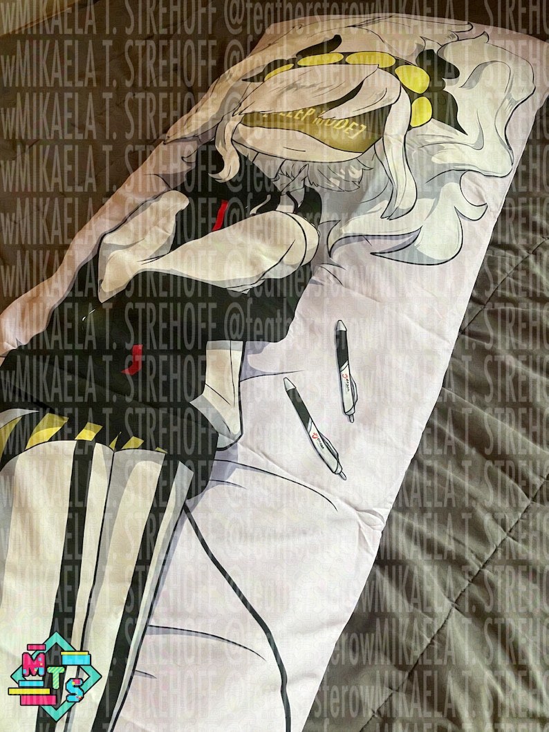 Op de afbeelding: Een lange rechthoekige kussensloop met een print van een anime-figuur met wit haar, gekleed in een zwart-wit gestreepte outfit met gele accenten. Het ontwerp bevat twee zwart-witte pennen die op de stof liggen.