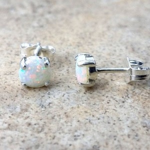 Può includere: Un paio di orecchini a perno in argento con pietre di opale bianco. Gli orecchini hanno un design semplice e sono perfetti per l'uso quotidiano.