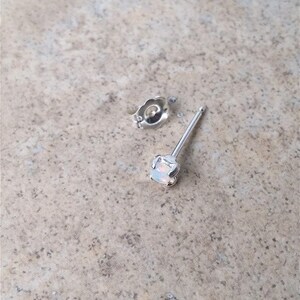 May include: A silver stud earring with a white opal gemstone.