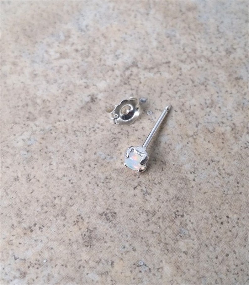 May include: A silver stud earring with a white opal gemstone.