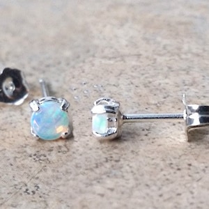 May include: A pair of silver stud earrings with small, round, white opal gemstones.