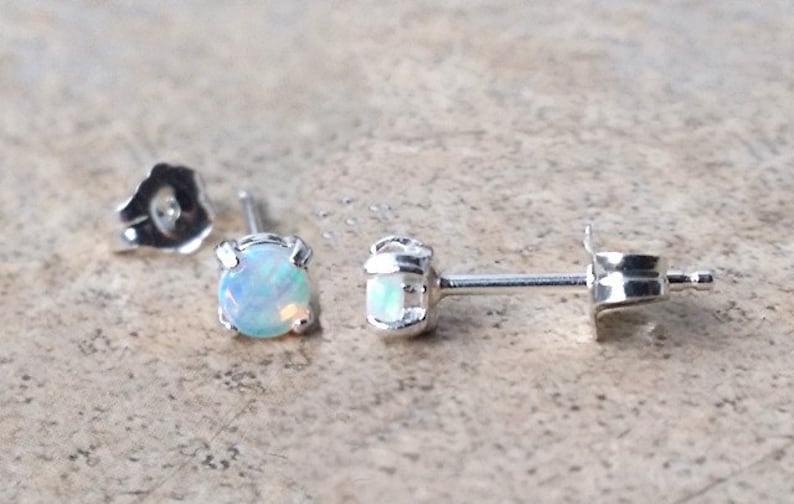 May include: A pair of silver stud earrings with small, round, white opal gemstones.