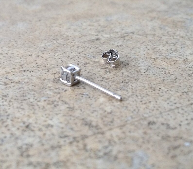 May include: A single silver earring with a small clear cubic zirconia stone.