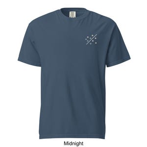May include: Midnight blue t-shirt with a small embroidered design on the upper left chest. The design features a diagonal white line with small, colourful dots. The shirt is made of a soft material and has a classic crew neck.