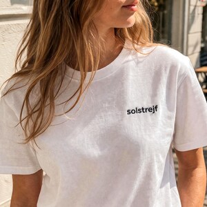 Minimalist white embroidered t-shirt with “solstrejf” text, Scandinavian style outfit, calm neutral aesthetic clothing for women