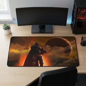 May include: A rectangular desk mat featuring a sci-fi scene with a figure holding a weapon, set against a backdrop of a planet with rings and a fiery sky. The mat is designed for use with a computer setup.