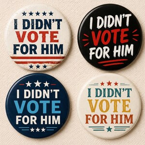 May include: Four round buttons with the text "I DIDN'T VOTE FOR HIM". The buttons are white, black, navy blue, and cream, with the text in red, white, blue, and yellow. Each button has stars and stripes.
