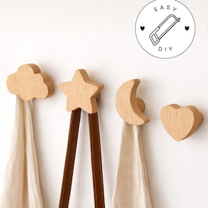 Puede incluir: Ganchos de pared de madera con forma de nube, estrella, luna creciente y corazón. Los ganchos sostienen tela y correas de cuero. La imagen incluye un gráfico circular con el texto "EASY DIY" y una ilustración de sierra.