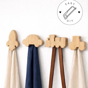 May include: Wooden wall hooks in the shape of a rocket, car, train, and tractor. Each hook is holding a different colored fabric or strap. A circular graphic with the text "EASY DIY" and a saw illustration is in the upper right corner.