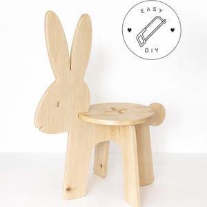 Op de afbeelding: Een lichtgekleurde houten stoel in de vorm van een konijn met lange oren, een ronde zitting met een kruisvormige uitsparing en een klein staartje. Een rond logo rechtsboven toont een zaagicoon met de tekst EASY DIY.