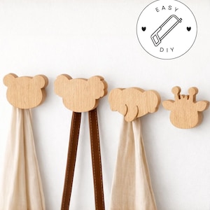 May include: Four wooden animal-shaped wall hooks. The hooks are light brown and feature a bear, koala, elephant, and giraffe design. Beige fabric hangs from the hooks. A circular graphic with the text "EASY DIY" is in the upper right corner.