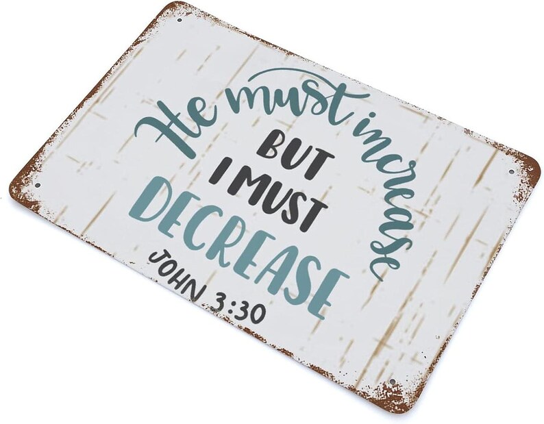 Op de afbeelding: Rechthoekig metalen bord met een verweerde witte achtergrond en bruine randen. Het bord toont de tekst "He must increase but I must decrease" in turquoise en zwarte letters, met "John 3:30" eronder.