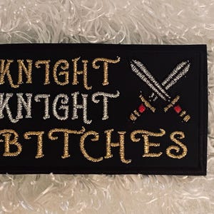 May include: Black embroidered patch with gold and silver lettering that reads "Knight Knight Bitches" with two crossed swords in the center.
