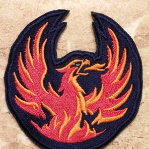 May include: A red and orange embroidered phoenix patch on a dark blue background. The phoenix is in a standing position with its wings spread out.
