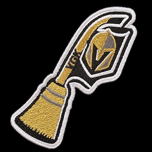 May include: Embroidered patch featuring a stylized hockey stick with a gold blade and handle, and a black and gold shield with a knight's helmet. The letters "VGK" are visible on the stick. The patch is outlined in white.