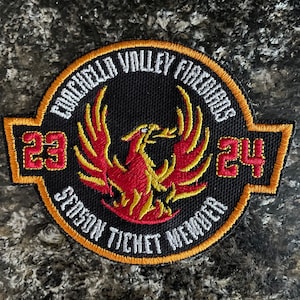 May include: A black embroidered patch with a red and gold phoenix design. The patch reads "Coachella Valley Firebirds Season Ticket Member 23-24".