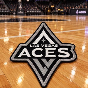 May include: A diamond-shaped embroidered patch featuring the Las Vegas Aces logo in black, white, and silver thread. The design includes the text LAS VEGAS ACES, a small four-pointed star, and a stylized LV monogram at the bottom point.