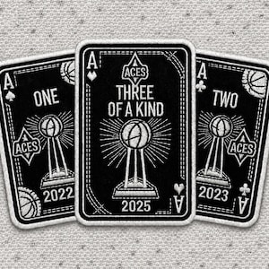 May include: Three black and white playing cards with the Ace of Spades symbol. The cards feature a basketball trophy design and the text "ONE", "THREE OF A KIND", and "TWO". The years 2022, 2025, and 2023 are also displayed.