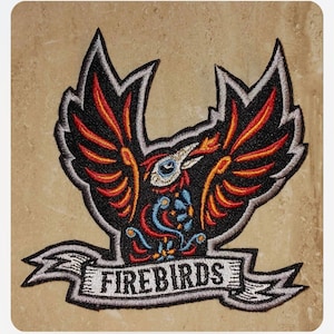 May include: Embroidered patch featuring a stylized red, orange, and black phoenix with blue eyes. The phoenix is surrounded by a white banner with the word "FIREBIRDS" in black lettering.