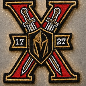 May include: An embroidered patch in the shape of a large letter X with red and gold stitching. It features two crossed swords, a central black shield with a gold helmet emblem, and the numbers 17 and 27 on small banners on the left and right sides.