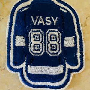 May include: Blue and white embroidered hockey jersey patch with the name "VASY" and the number "88" on the back.