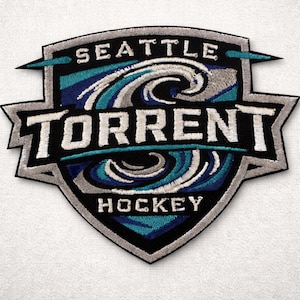 May include: Embroidered patch featuring the words "SEATTLE TORRENT HOCKEY" in white lettering. The patch has a shield shape with a black border and a design of blue and white waves. The background is white.